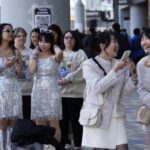 People wait in line near a poster to have their photo taken with others, right, in front of a selfie before Taylor Swift's concert at the Tokyo Dome in Tokyo, Saturday, Feb. 10, 2024. (AP Photo /Hiro Komae)